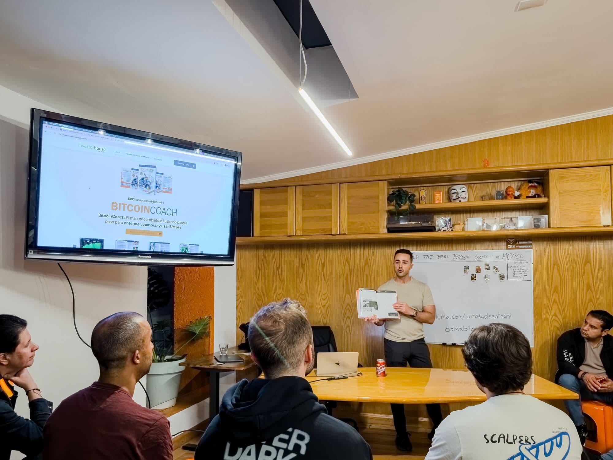 A speaker holds up the BitcoinCoach book during a talk