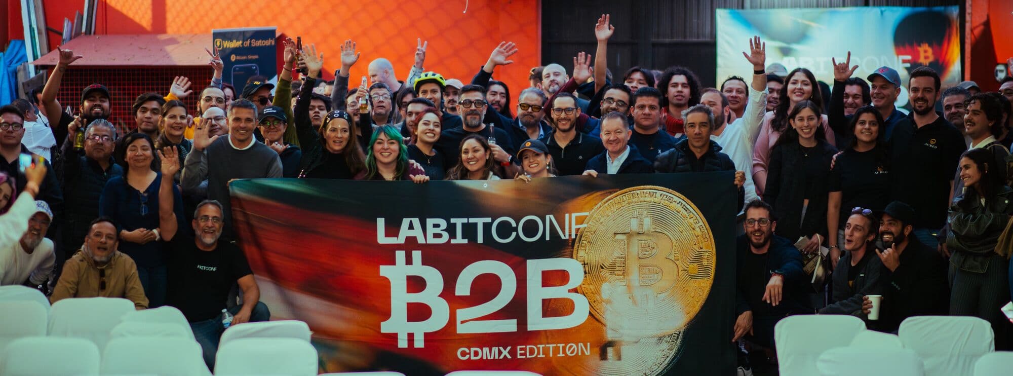 The LABITCONF B2B CDMX crowd, hands up, behind the event banner