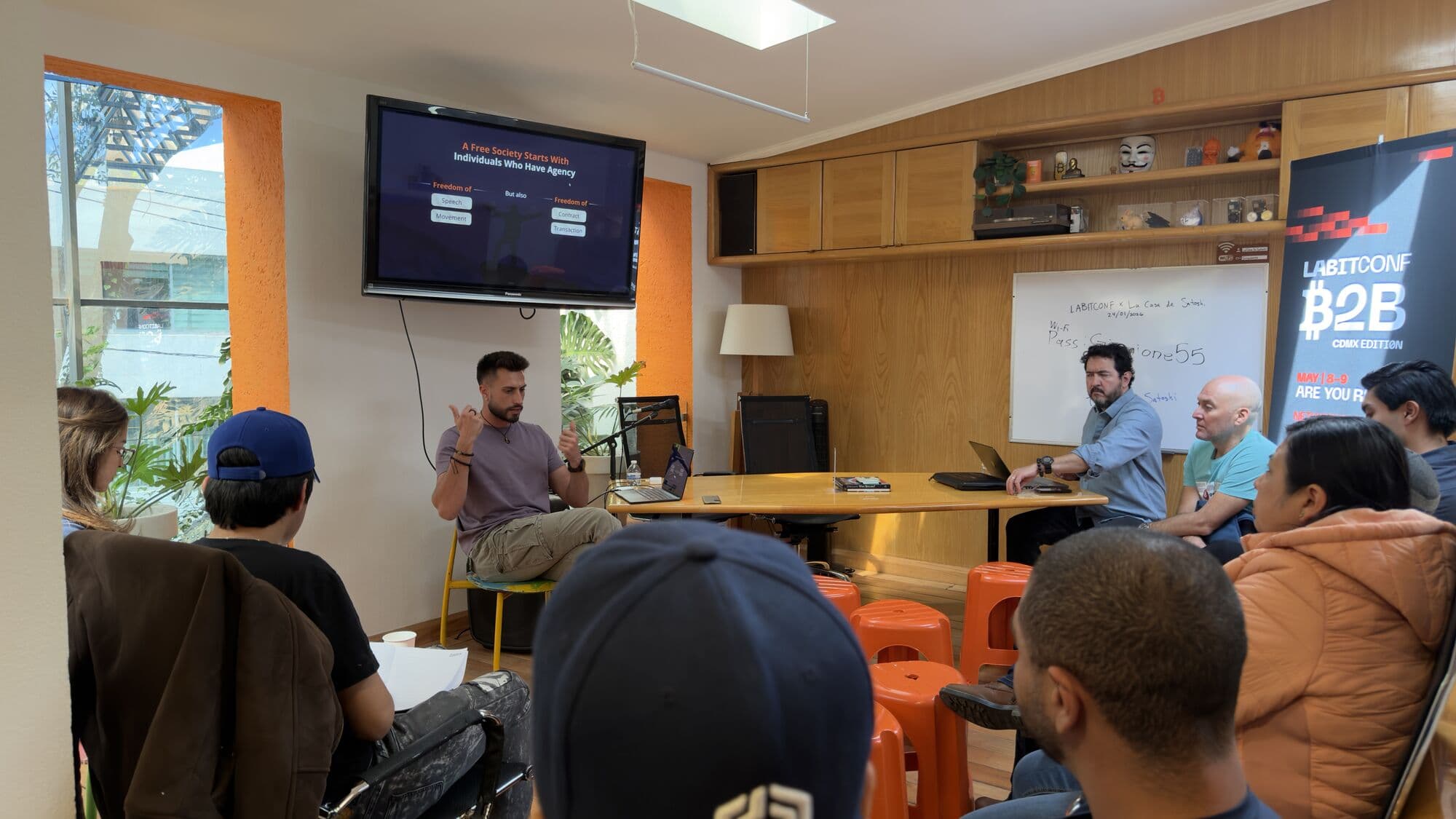 A talk in the main room, audience on orange stools