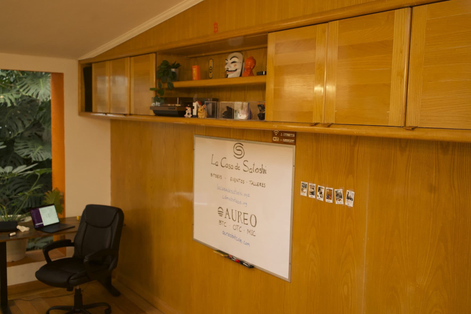 El pizarrón del salón principal con La Casa de Satoshi y Aureo escritos, y un escritorio junto a la ventana